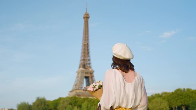 Young tourist with a bouquet of flowers on the bridge near the Eiffel Tower