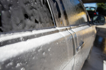 self car wash, cleaning foam dripping on car body