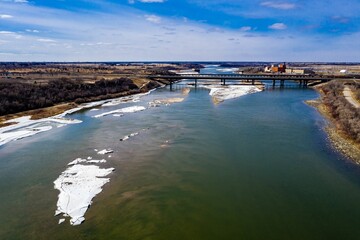 Aerial shot of the frozen South Saskatchewan River and a bridge over it under the blue sky