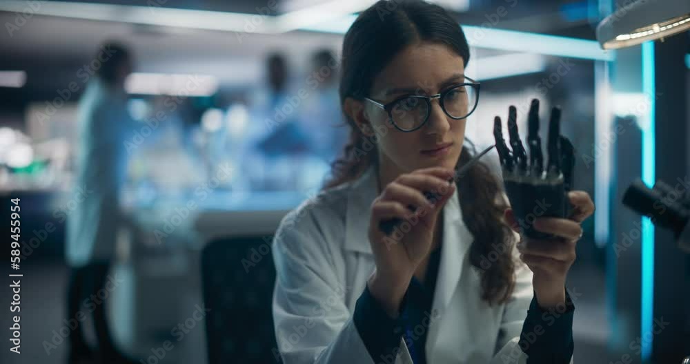 Leinwandbilder Beautiful Young Female Scientist Working on a Prosthetic Robotic Hand. Focus Switching to a Diverse Team of Industrial Specialists Working on Advanced Remotely Controlled Mobility Robot Dog
