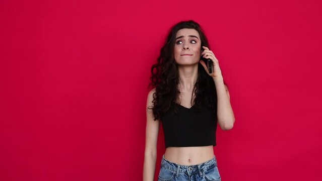 Young  woman get an phone call wait answer and explose in victory gesture  isolated on red background