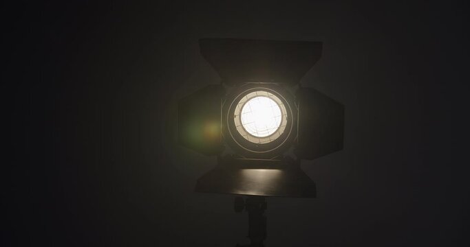 Video studio Fresnel lens spotlight on black background. lights slowly turn on. Close up.