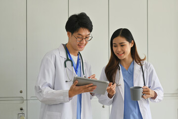 Two professional doctors looking at digital tablet and discussing on laboratory test. clinic, health care and medicine concept