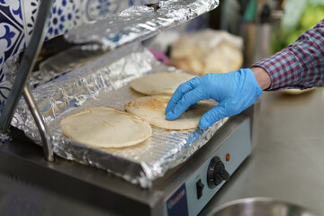 Cook turning pita bread on electric grill press. Kitchen worker preparing traditional Greek sandwiches in a fast food restaurant