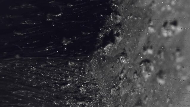 Vertical video. Glitter fluid. Ink splash. Cascade texture. Black sparkling dust dirt liquid drip flow motion on cube angle dark abstract background.