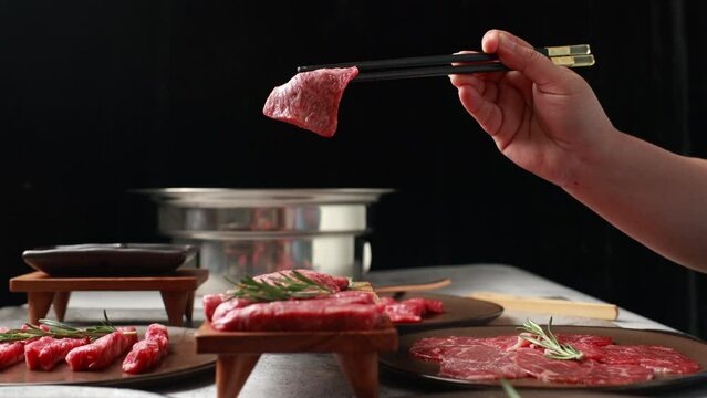 Slow motion VDO. Woman hand using chopsticks pinking up wagyu beef. Grilled japanese premium wagyu beef Sirloin steak