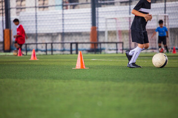 Children playing control soccer ball tactics cone on a grass field with for training background