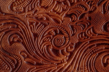 Dark brown red old cracked  leather with floral print. Sample of rough leather with ornament.