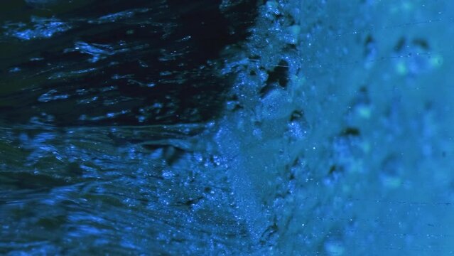 Vertical video. Paint drip. Glitter fluid. Ice cascade. Blue color sparkling flakes texture ink fall motion on cube angle abstract background.