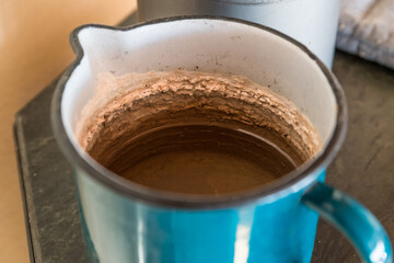 Ein blauer Becher aus Emaile mit Wasser und sehr starken Kalkablagerungen auf der Innenseite,...