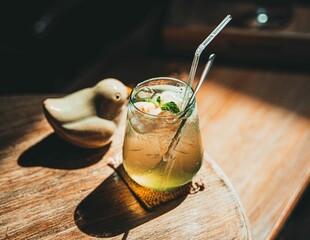 High angle shot of a glass with an iced delicious cocktail and a straw on a wooden table