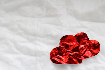 Two red heart shape Crumpled are placed on white paper.