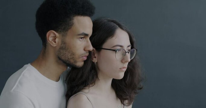 Slow motion portrait of man and woman with serious faces standing close on grey background. Relationship and human emotion concept.