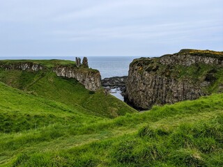 Fototapeta na wymiar Dunseverick castle with green grass on rocky cliffs gloomy seascape background