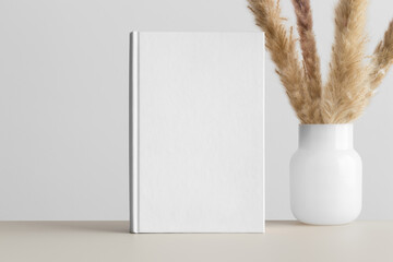 White book mockup with a pampas decoration on the beige table.