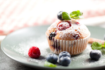 Freshly baked muffins with powdered sugar and fresh berries