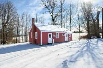 Beautiful red wooden house with a cloudy blue sky in the background on a sunny winter day