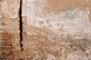 Old wall with large crack and peeling plaster