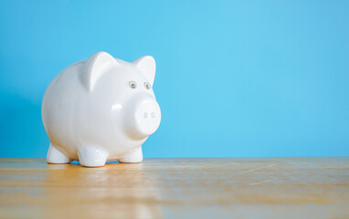Fototapeta premium White Piggy bank on blue background with copy space. Saving money concept. 