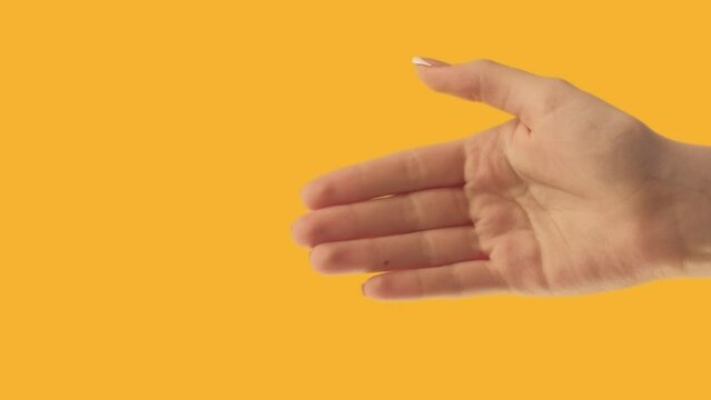 Vertical video. Goodbye gesture. Farewell sign. See you later. Female hand waving bye isolated on orange copy space background.