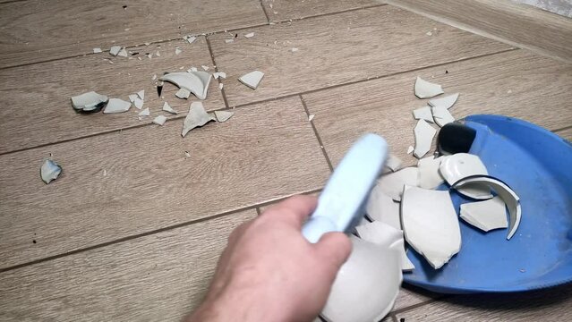 A housekeeper sweeps the broken vase with a broom