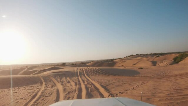 4K POV of a vehicle dune bashing on the sand dunes of the Thar desert at Jaisalmer in Rajasthan, India. Car moves on the desert during the day. Extreme adventure in the desert background.