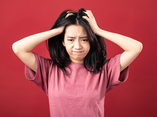 A portrait of a young Indonesian (Asian) woman wearing a pink shirt, looking dizzy and holding her...