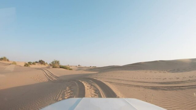 4K POV of a vehicle dune bashing on the sand dunes of the Thar desert at Jaisalmer in Rajasthan, India. Car moves on the desert during the day. Extreme adventure in the desert background.