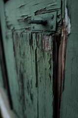 Closeup shot of an old wooden shutter door with many cracks painted in green