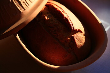 Home baked bread in a traditional clay form with warm sunlight