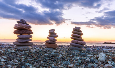 three towewrs or turrets of stone in a nice empty sea beach with coast line guring sunset or...