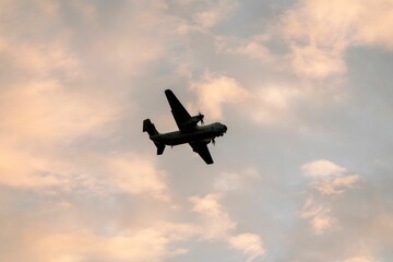 Fototapeta na wymiar Low angle shot of a silhouette of the Coronado San Diego military airplane flying in a sunset sky