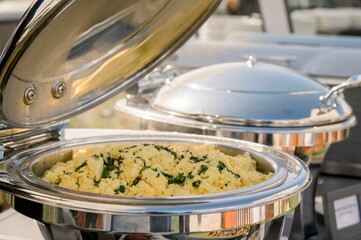 Closeup shot of a large silver pot of scrambled eggs with greens at an event