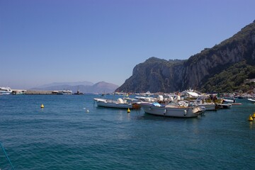 Beautiful shot of boats on the water near rocky cliffs on Capri Island, Naples, Italy
