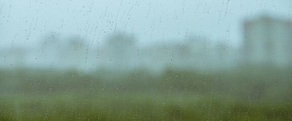 Atmospheric minimal backdrop with rain droplets on glass. Wet window with rainy drops and dirt...