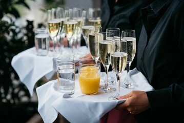 Waiter with sparkling wine, water and orange juice