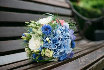 Flower bouquet decorated with greenery on a wooden bench.