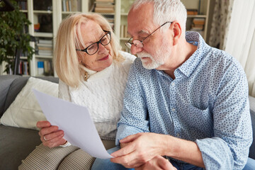 Senior couple reading retirement plan contract at home - obrazy, fototapety, plakaty