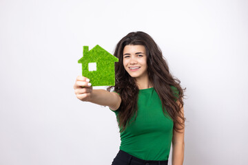 Happy house buyer. A young girl holds a model of a green house in her hands. The concept of green energy, ecology.