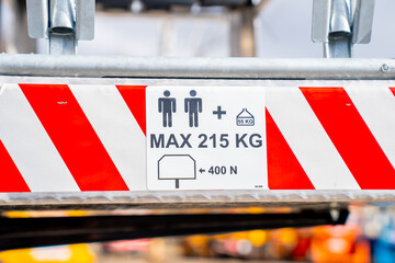 Maximum weight capacity warning sign with 215 Kilograms on industrial lift platform