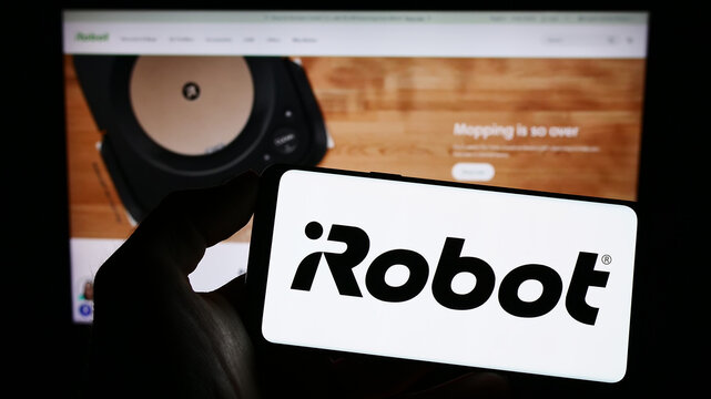 Stuttgart, Germany - 03-31-2023: Person holding cellphone with logo of US technology company iRobot Corporation on screen in front of business webpage. Focus on phone display.