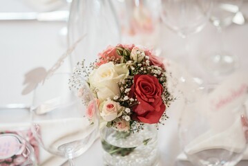 Selective focus of a wedding bouquet with red and white flowers on a glass pot, blurred background