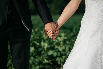 Closeup of the bridegroom holding bride's hand while standing next to her