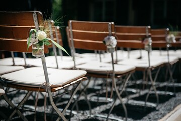 Closeup of the line of wooden chairs with floral decorations ready for weeding