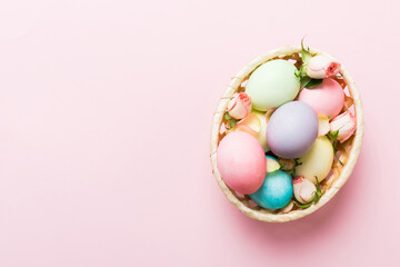 Happy Easter. Easter eggs in basket on colored table with yellow roses. Natural dyed colorful eggs background top view with copy space