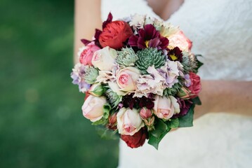 Closeup of a wedding bouquet and a bride holding it blurred background