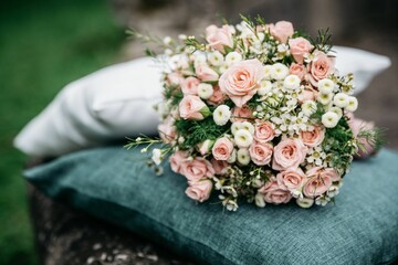 Closeup shot of the pink and white flowers bouquet on a gray pillow with blur background