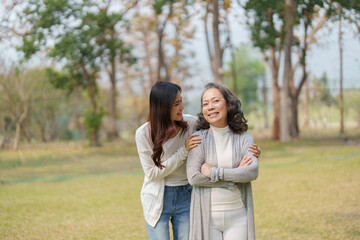 Grown daughter with aging mother showing love and walking together in the parkland