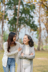 Obraz premium Grown daughter with aging mother showing love and walking together in the parkland