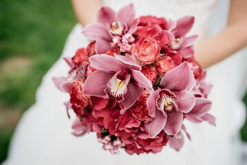 Closeup of a bride in white dress holding a beautiful pink flowers' bouquet